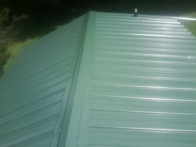 New green metal panels meeting at the ridge of a roof — Flat Roof Repair work by our crew in Tavares