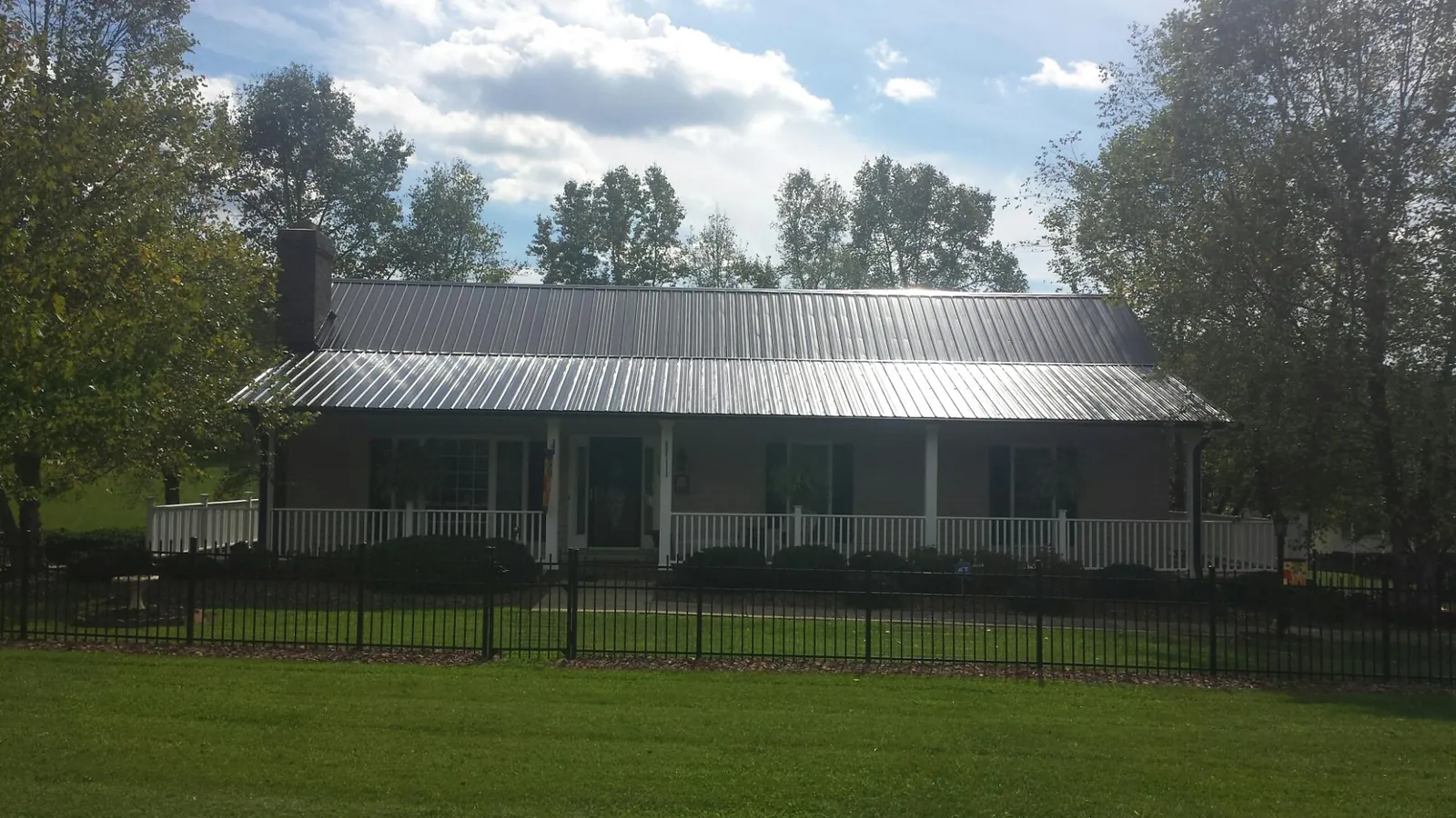 Gray metal roof on a brick ranch with a full width front porch — Gutter Guard Installation work by our crew in Tavares