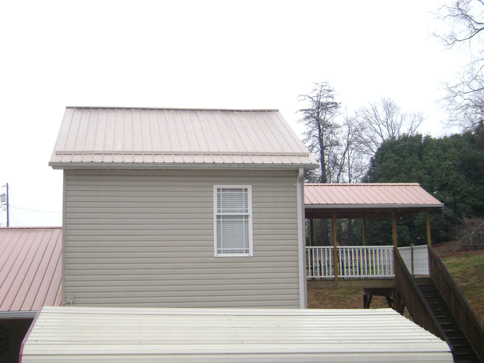 Tan metal roofs on a two story addition and attached porch, from a Roof Replacement job in Tavares