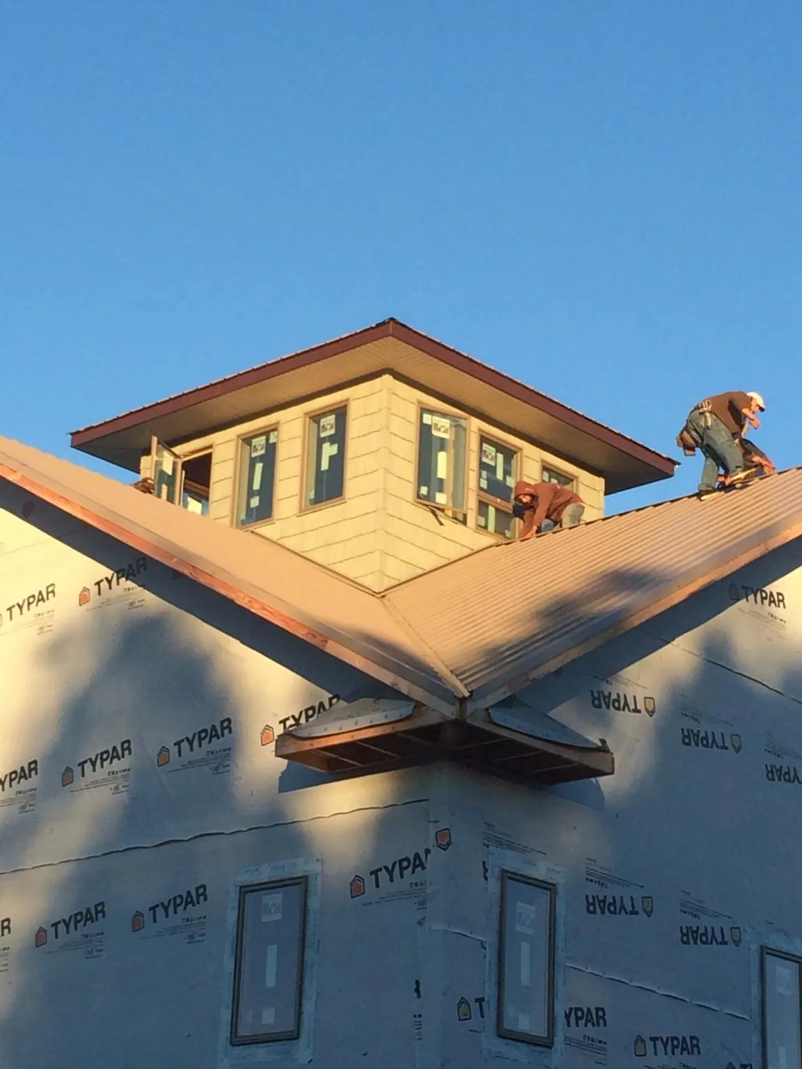 Roofers working around a rooftop cupola on a new metal roof at sunset — Roof Waterproofing in Tavares by Roofing Brothers